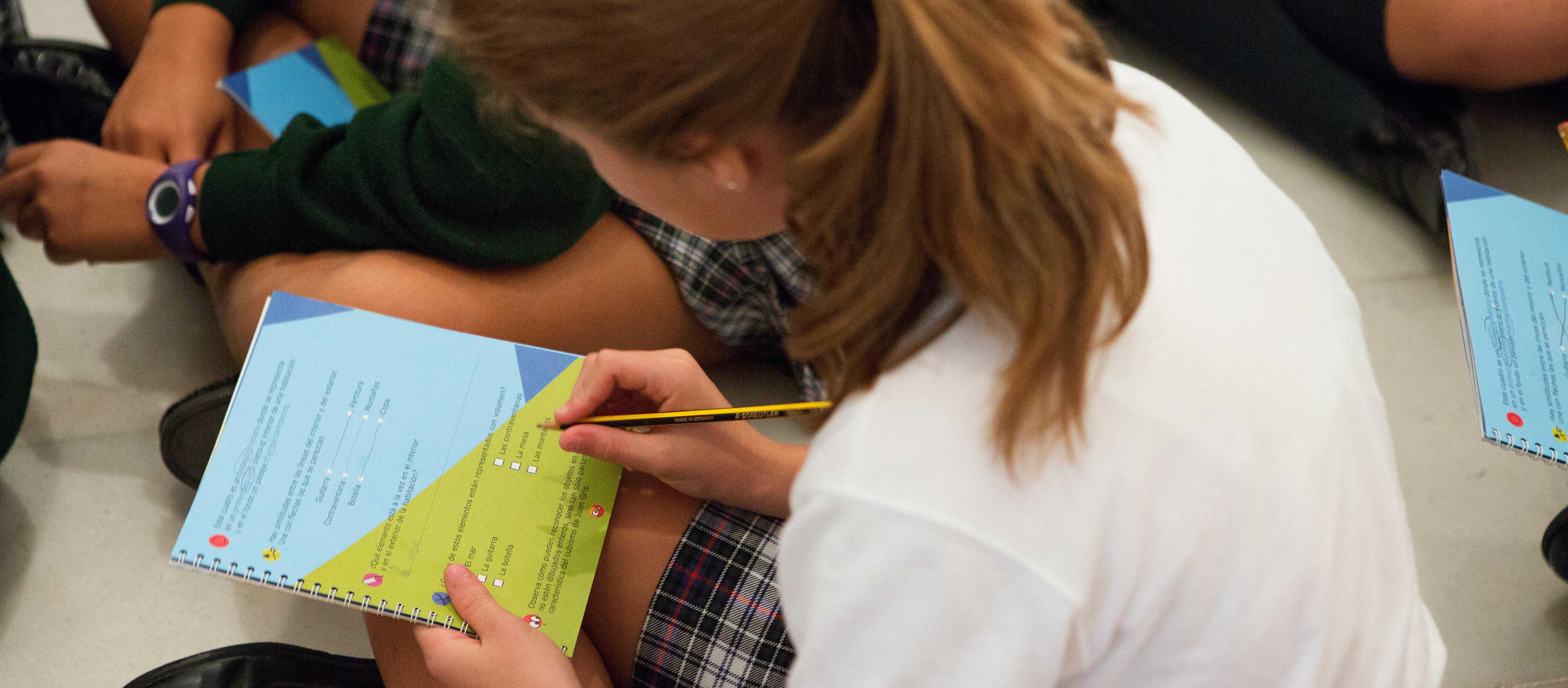 Niña rellenando un cuaderno en una visita cultural